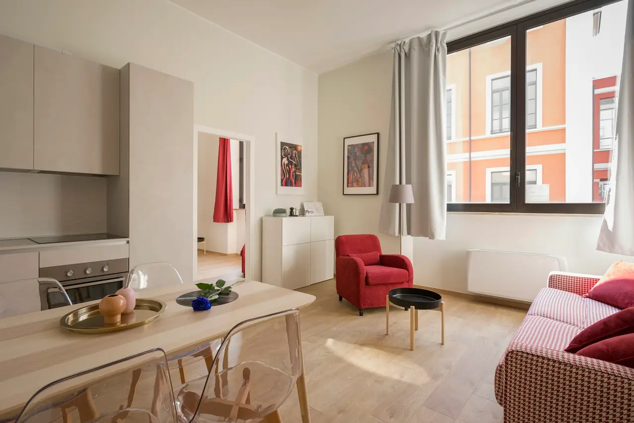 A compact, bright studio apartment with a dining table and sofa